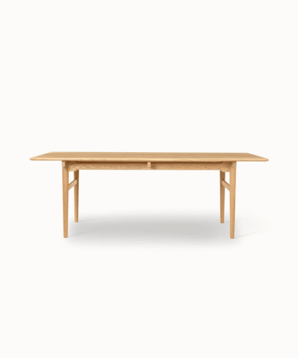 Nilaya solid teak dining table with rounded legs and floating tabletop, handcrafted with rich oil polish and seamless extensions for 6 to 12 guests.