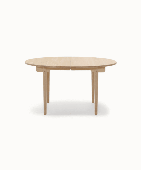 Samvara teak dining table with elliptical top and tapered legs.