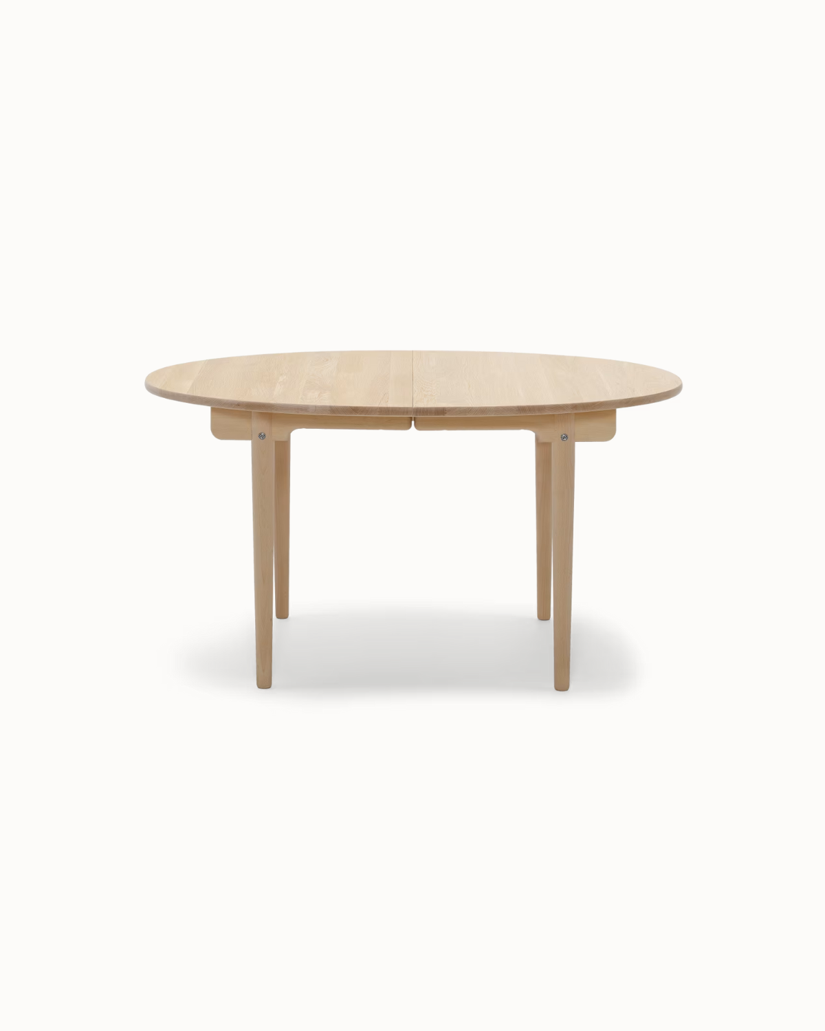 Samvara teak dining table with elliptical top and tapered legs.