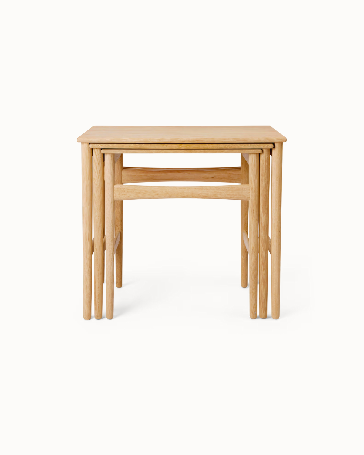 Set of three solid teak Yugma nesting tables with tapered legs and oil finish, shown stacked and arranged in modern interior settings.